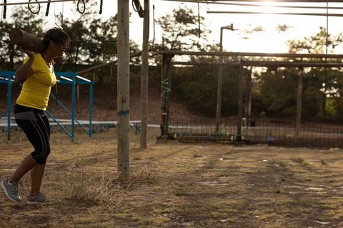 Woman training with wooden log in outdoor obstacle course