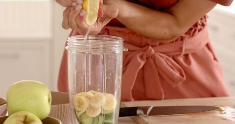 Preparing Fresh Smoothie with Sliced Produce in Sunlit Kitchen