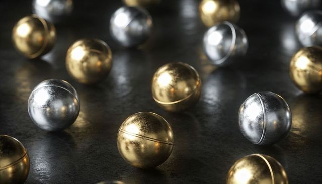 Brushed gold and silver metal spheres reflecting light on dark textured surface
