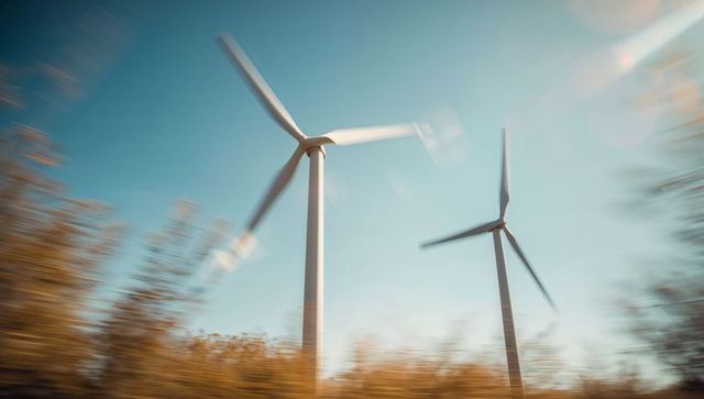 Wind Turbines Spinning Above Blurred Scenery in Clear Sky