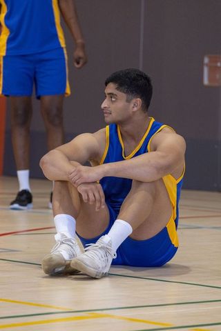 Diverse Male Basketball Players Resting on Indoor Court