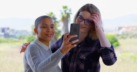 Smiling Friends Capturing Selfie Outdoors on Sunlit Terrace