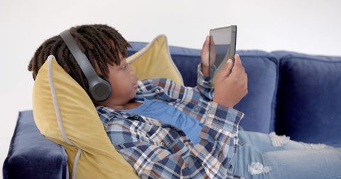 Boy Enjoying Tablet with Headphones on Cozy Sofa - Download Free Stock Images Pikwizard.com