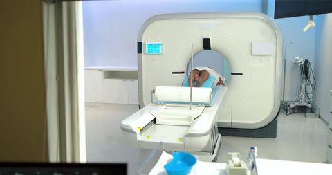 Adult patient lying on ct scanner table entering gantry in sterile radiology room