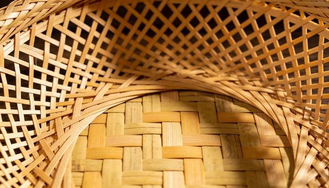 Handwoven bamboo basket close-up showing plaited base and lattice sides, natural texture