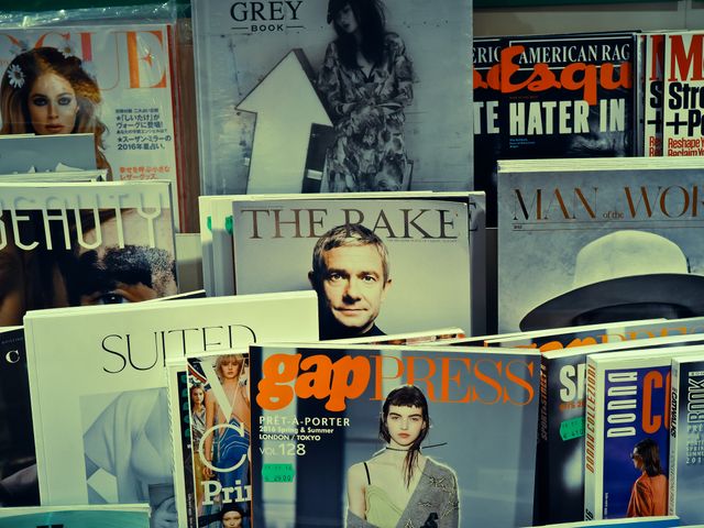 Numerous fashion and lifestyle magazines are displayed on a shelf, showcasing various covers. Each cover features different styles, models, and articles related to fashion, beauty, and lifestyle. This is ideal for representing print media, the importance of fashion in literature, and bookstore advertising.