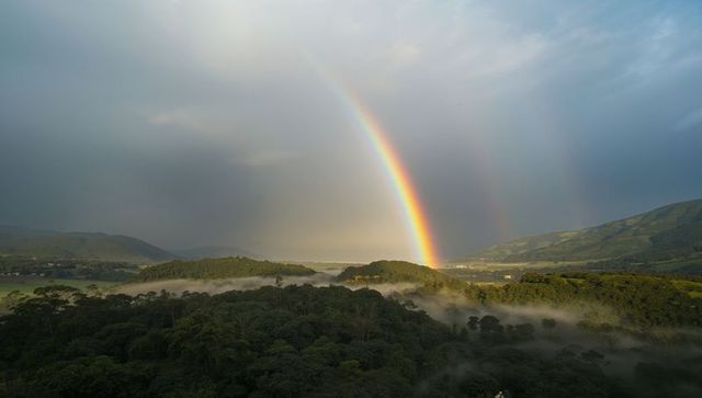Vibrant double rainbow arching over serene misty hills