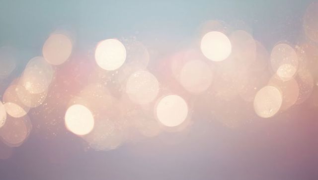 Glowing pastel bokeh lights forming dreamy lilac and blue gradient background with glitter