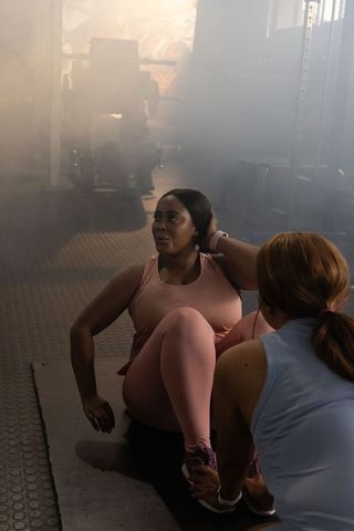 Diverse female partners doing core workout on gym mat with moody atmospheric lighting