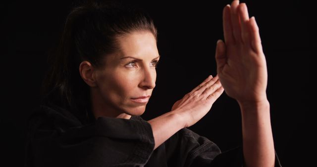 Focused Female Martial Artist Practicing Karate on Black Background - Download Free Stock Images Pikwizard.com