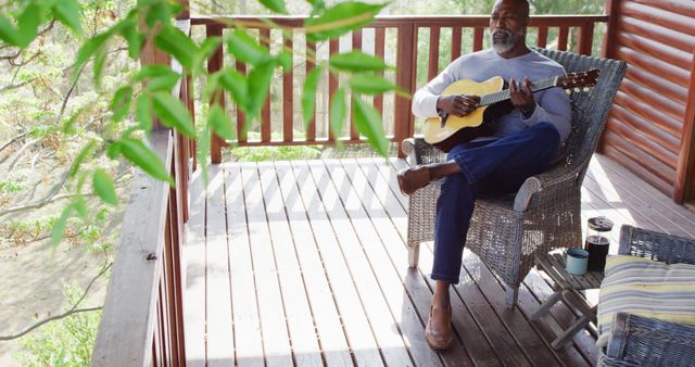 Senior african american man on balcony in log cabin playing guitar - Download Free Stock Photos Pikwizard.com