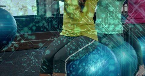Women balancing on stability balls during group fitness class with digital circuit overlay