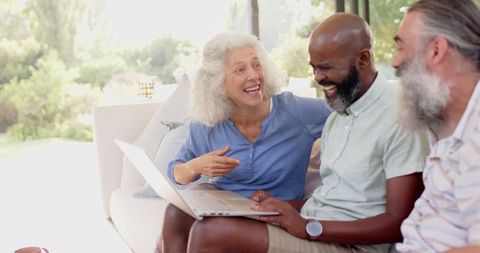 Senior Friends Using Laptop Together in Living Room