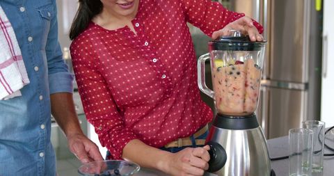 Couple blending fresh smoothies in modern home kitchen