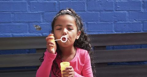 Joyful Child Blowing Bubbles Against Blue Brick Wall - Download Free Stock Images Pikwizard.com