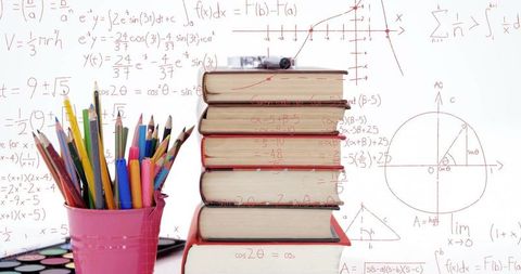 Stack of Books with Art Supplies Among Math Formulas Background