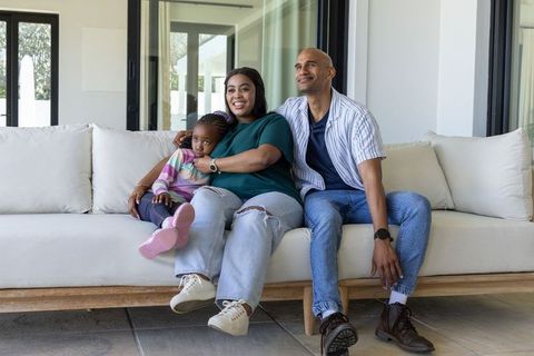 African american family relaxing on sofa at home smiling parents with preschool child