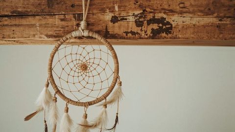 Bohemian dreamcatcher with feathers on rustic wooden beam