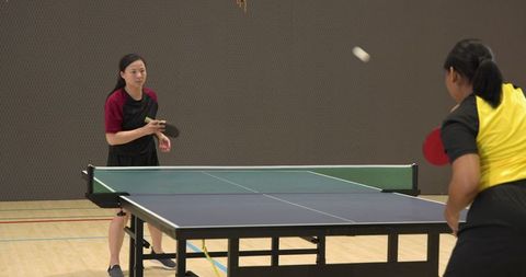 Women Playing Competitive Table Tennis in Gym