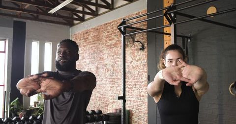 Diverse Workout Partners Stretching in Industrial Gym