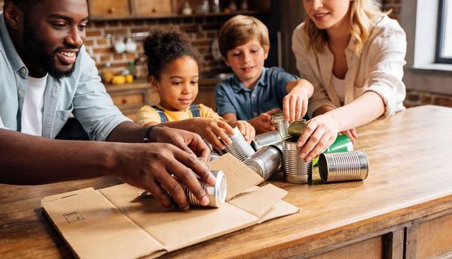 Family packing canned food for donation on kitchen island, kids helping parents volunteer