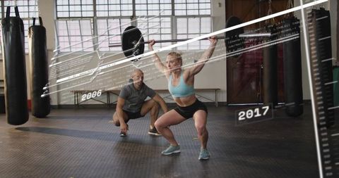 Female athlete performing overhead squat with barbell while coach spotting and data overlay