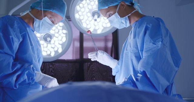 Side view of a Caucasian male and female surgeon at work in a hospital operating theatre, talking about the patient.