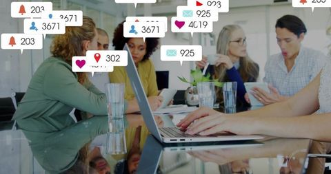 Hands typing on laptop with social notifications over collaborative business team meeting