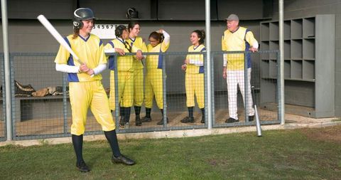 Teen girls in dugout supporting female baseball batter