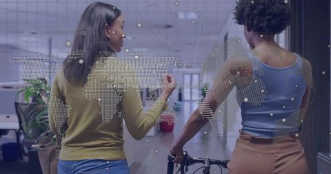 Two Professional Women Conversing in Futuristic Office with World Map Overlay