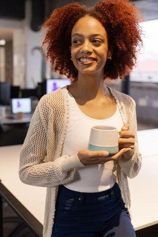 Smiling Professional Holding Coffee Cup in Modern Office