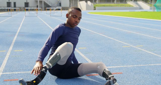 Athlete with a prosthetic leg stretches on a track field. His determination exemplifies resilience and the spirit of adaptive sports.
