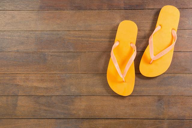 Pair of yellow beach flip flop slipper on wooden board