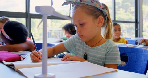 Young Schoolgirl Studying Near Wind Turbine Model in Classroom