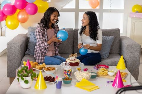 Mother and teen daughter preparing balloons and cake for colorful birthday celebration