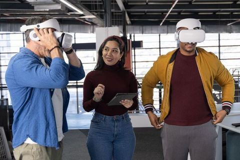 Multigenerational team testing virtual reality headsets in modern open-plan workspace