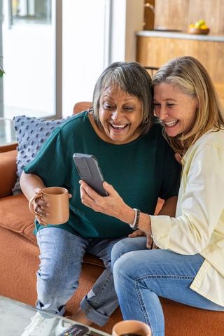 Senior friends enjoying digital moment in cozy living room