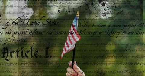 Hand holding small american flag with us constitution overlay