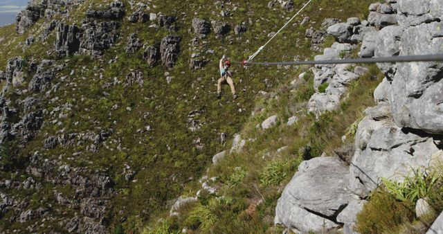 Caucasian man ziplining with safety belts in mountains, copy space. Ziplining, active lifestyle, safety and nature concept, unaltered.