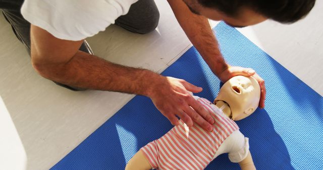 A man is practicing CPR on a training mannequin, simulating a life-saving procedure, with copy space. Such training is crucial for emergency response and can significantly improve survival rates in real-life situations.
