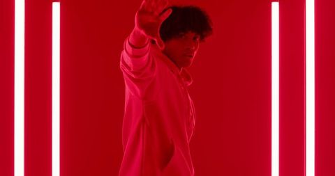 Urban Fashion Vibe: Man Posing Amid Neon Red Lights