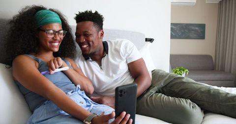 Couple celebrating positive pregnancy test, sharing joy via video call