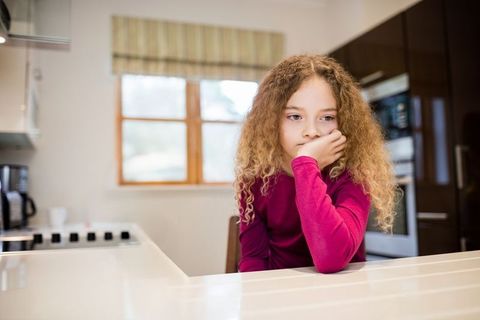 Thoughtful child relaxing at home kitchen counter