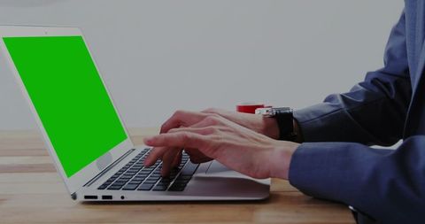 Professional typing on laptop with green screen for mockup and remote work