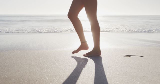 Person Walking on Sunny Beach with Calm Waves - Download Free Stock Images Pikwizard.com