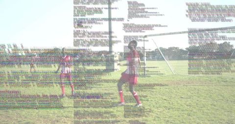 Young Soccer Player Standing by Goal Kicking Ball on Sunlit Field in Red Uniform