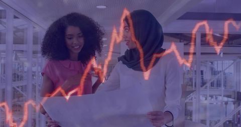 Diverse Women Collaborating on Blueprint and Analyzing Graph Trends