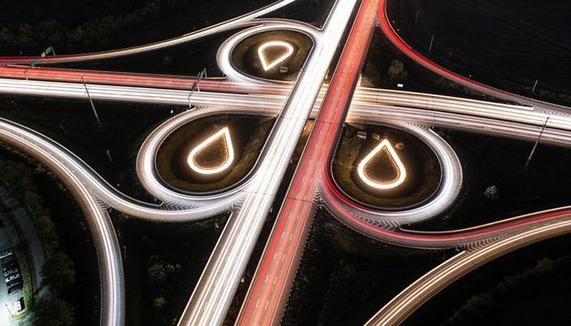 Aerial night long exposure highway interchange with teardrop loops and dynamic light trails