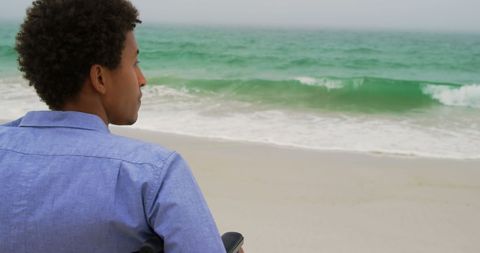 Man in Wheelchair Gazing at Ocean on Tranquil Beach