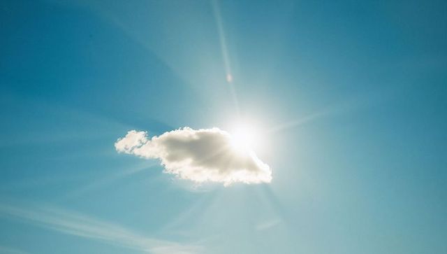 Serene Cloud Obscuring Sun in Clear Blue Sky with Radiating Sunbeams